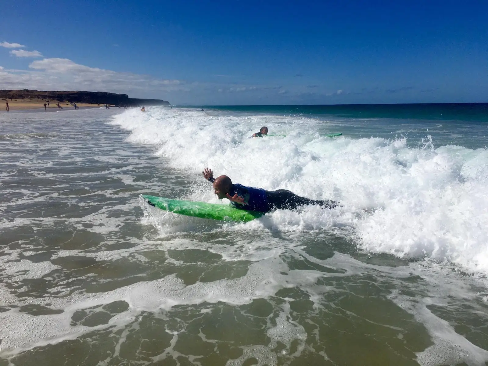 Anfänger surft Weißwasserwelle im Surfkurs auf Fuerteventura