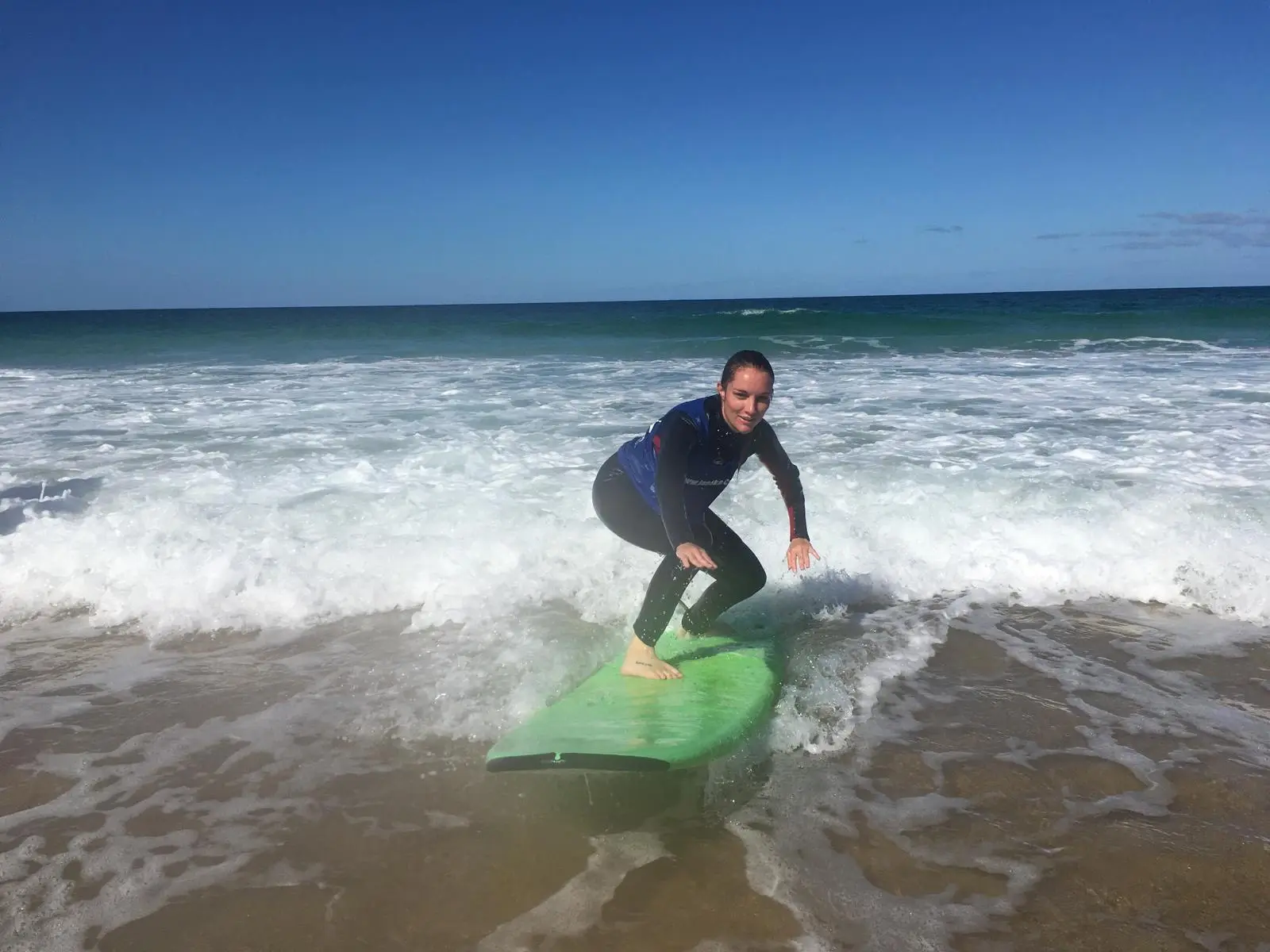 Anfänger steht seine erste Welle im Surfkurs in Corralejo auf Fuerteventura